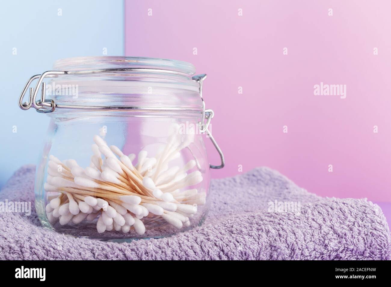 Cotton tipped swabs in a glass jar on color background.Natural bath products. Biodegradable