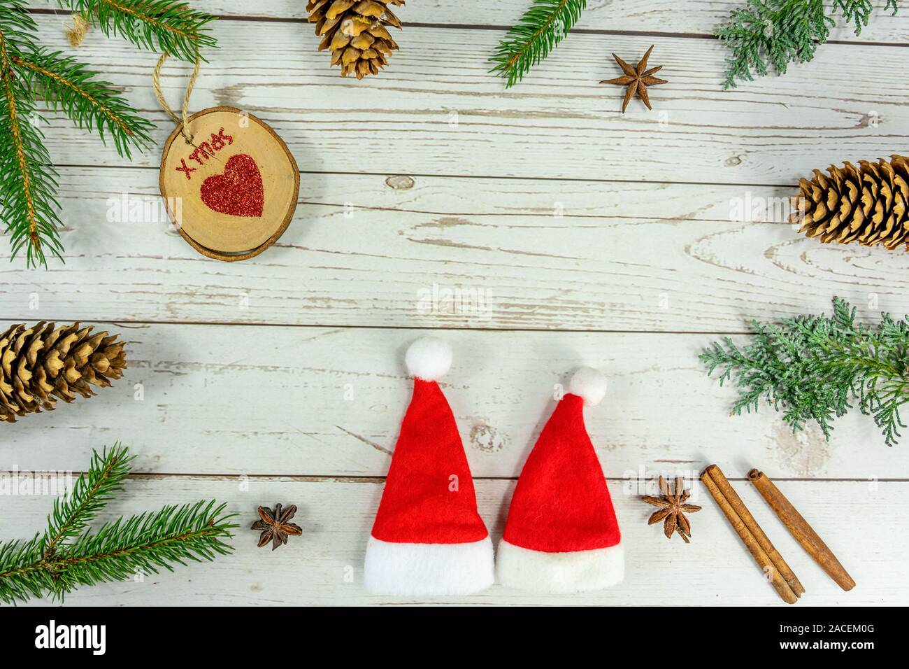 Christmas frame background flat lay on white wood with other natural decoration and two santa hats . Stock Photo