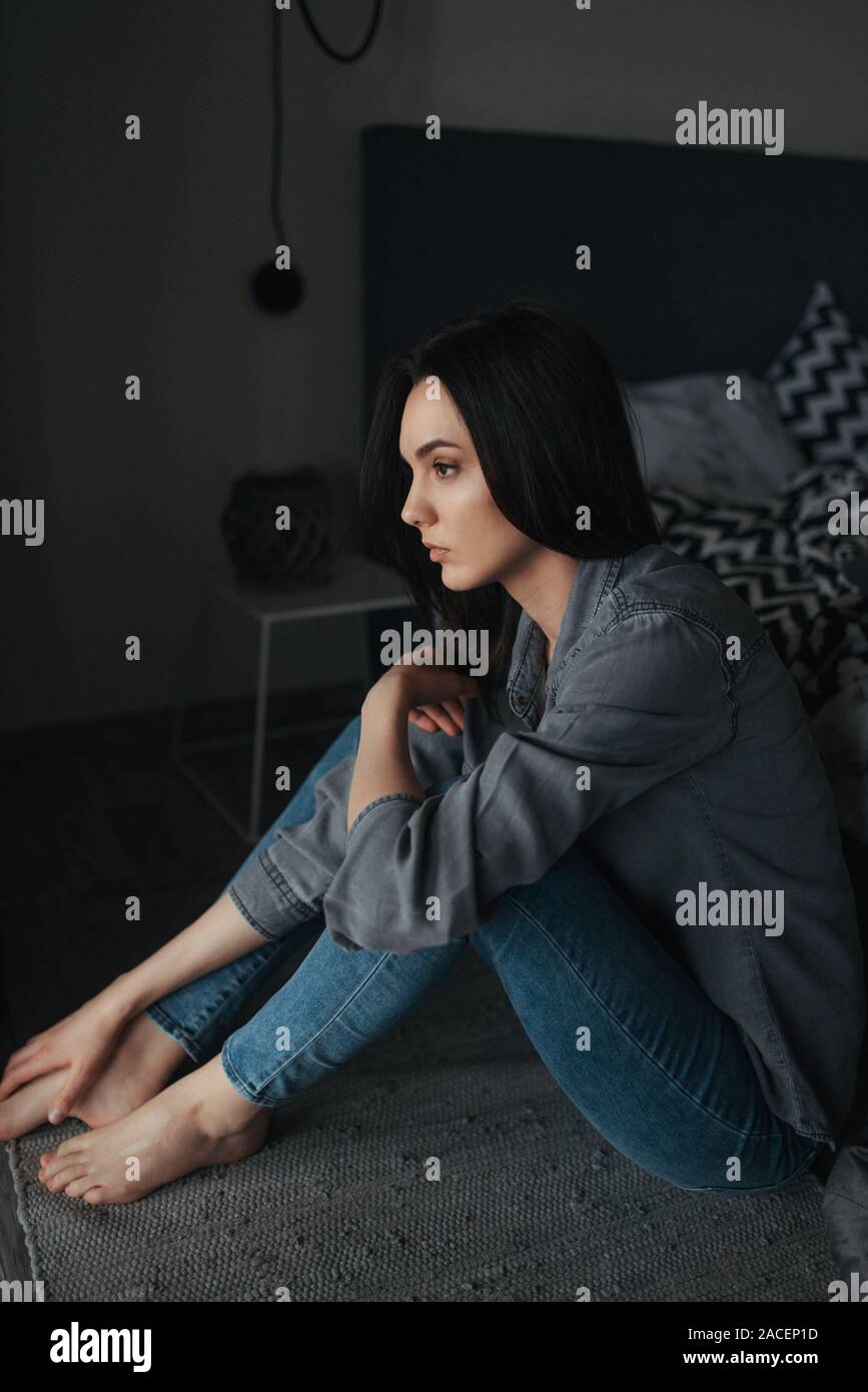A young lonely woman sitting on floor in a dark room Stock Photo - Alamy