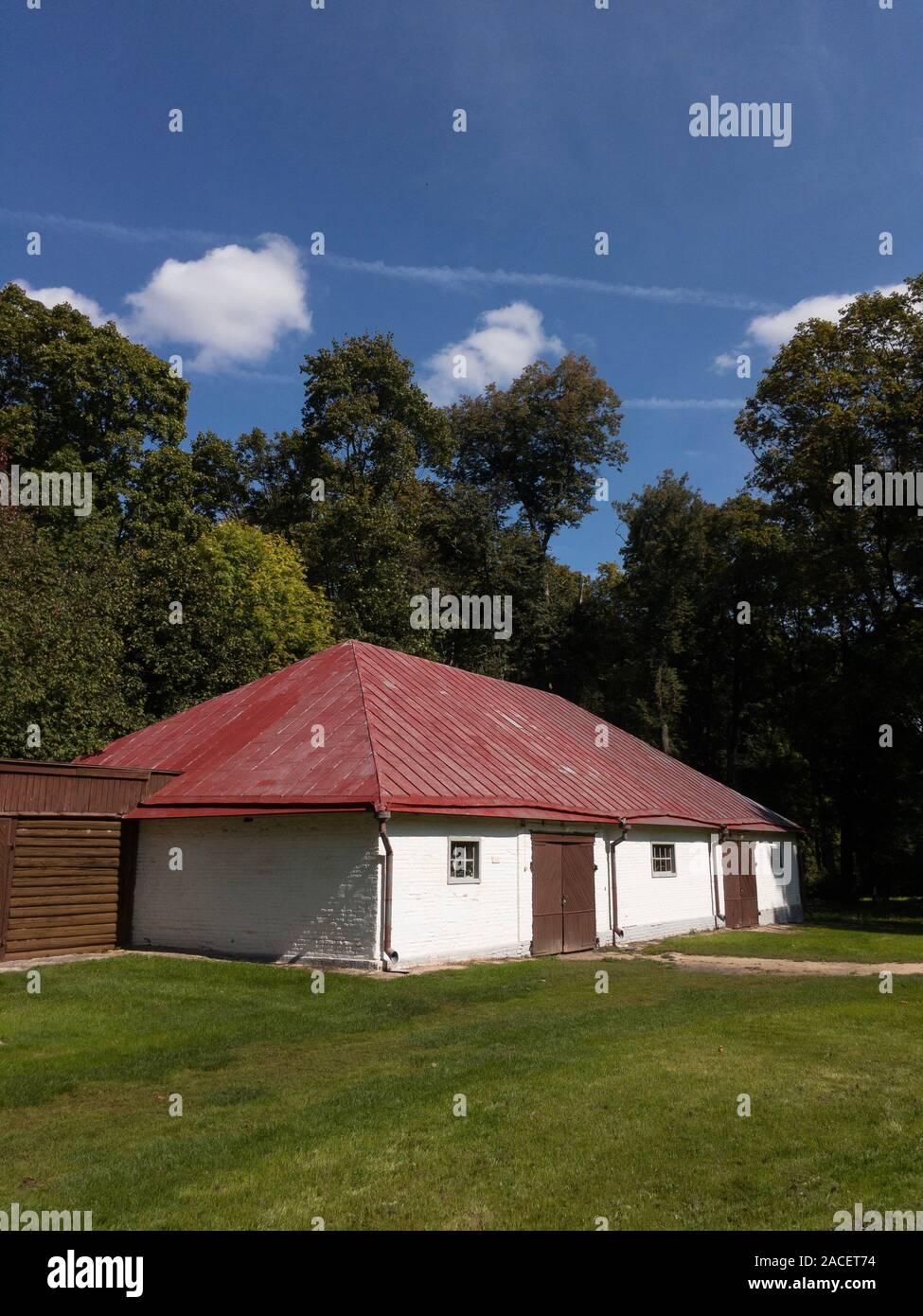 Old brick building on green lawn. Stable in Spasskoe-Lutovinovo, Turgenev's estate in sunny summer day copy space Stock Photo