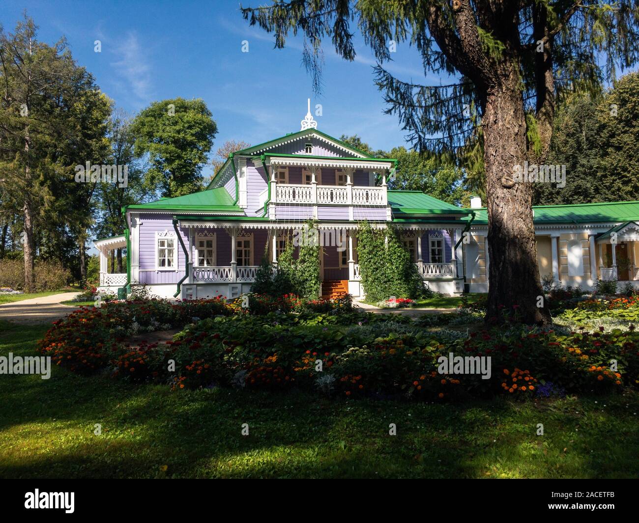 Old cozy wooden house and flowerbed under high trees in Spasskoe-Lutovinovo, Turgenev's estate in sunny summer day copy space Stock Photo