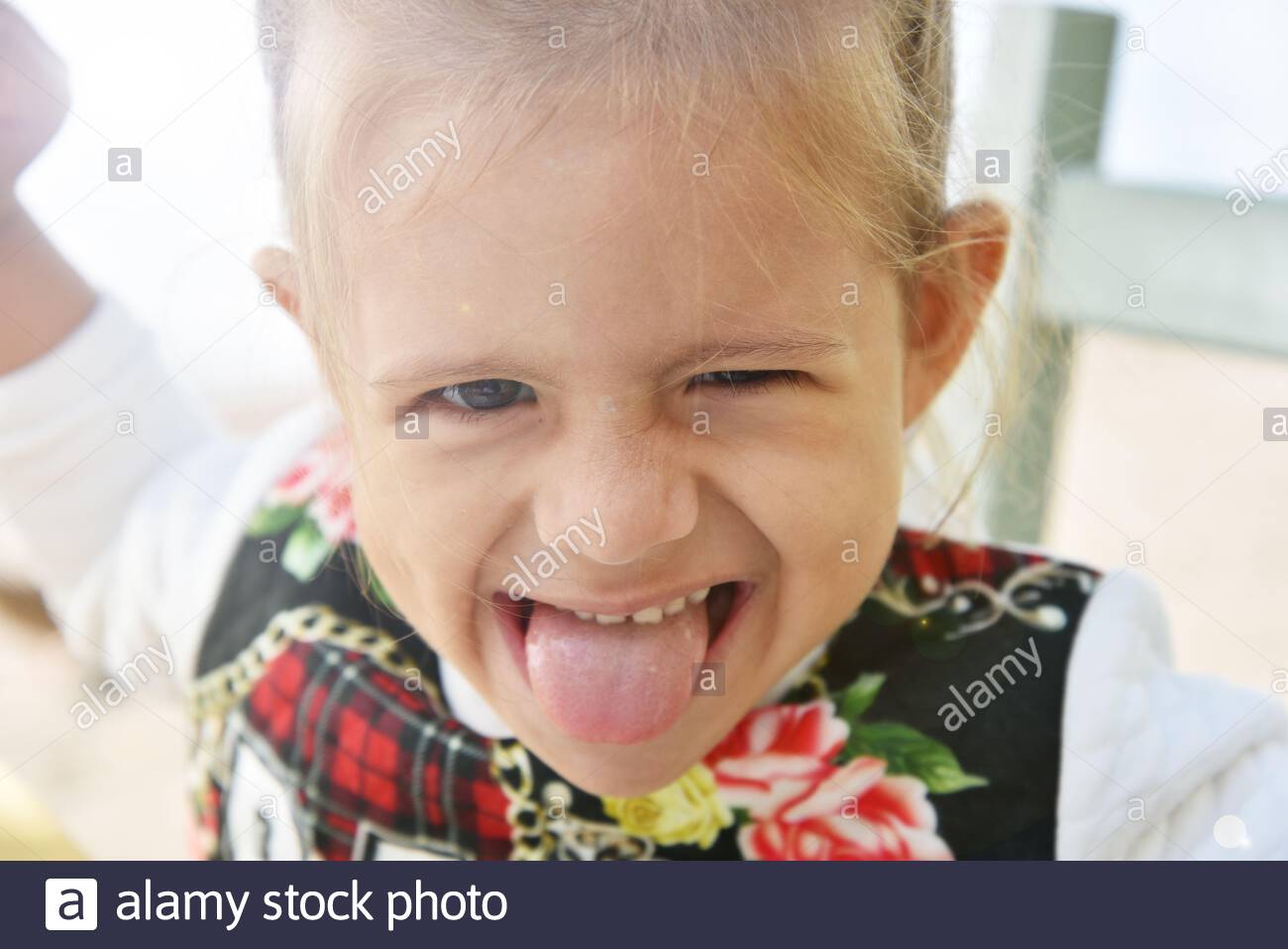 Pretty Little Girl With Blonde Hair Shows Tongue Child With