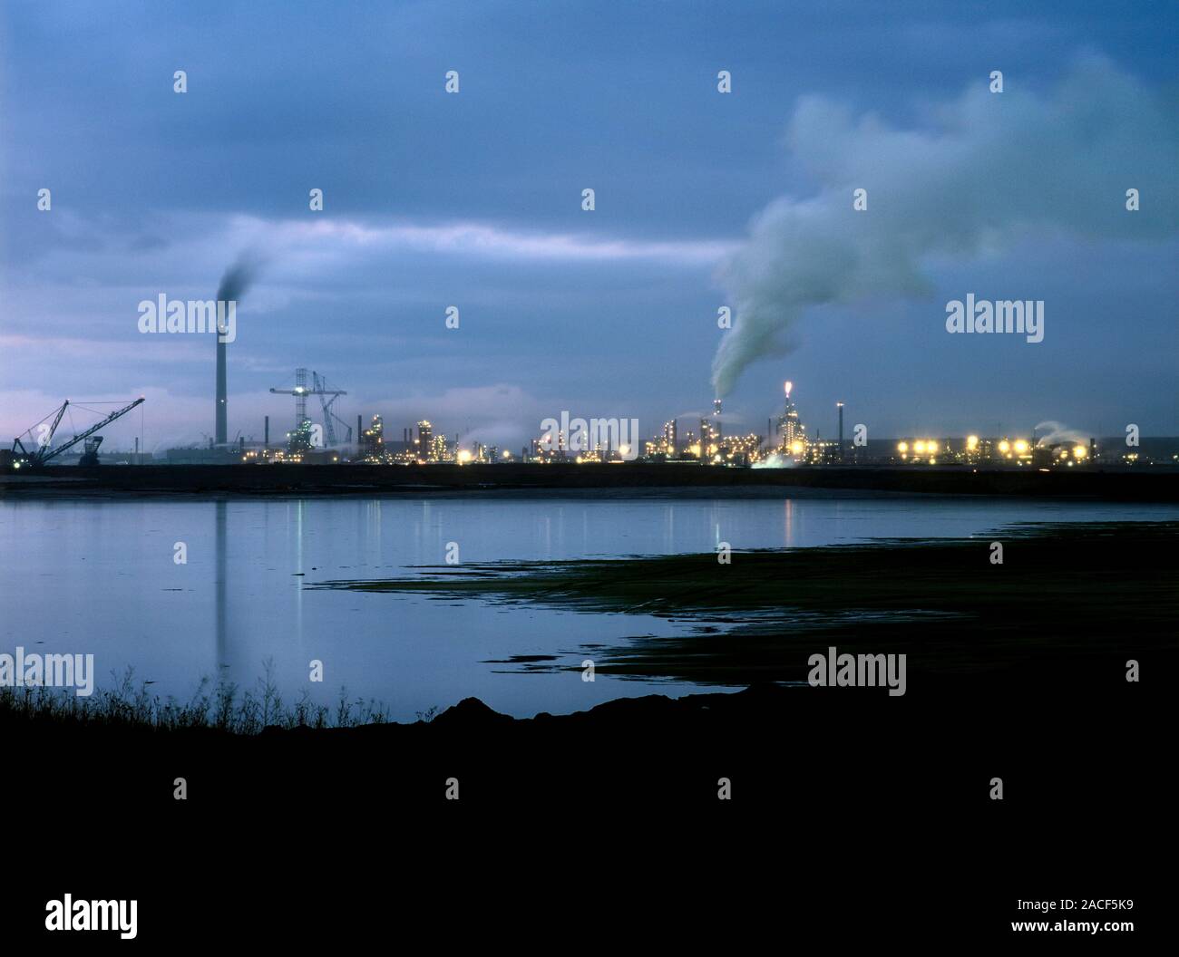 Oil sands refinery, Canada, at twilight. The water in the foreground is