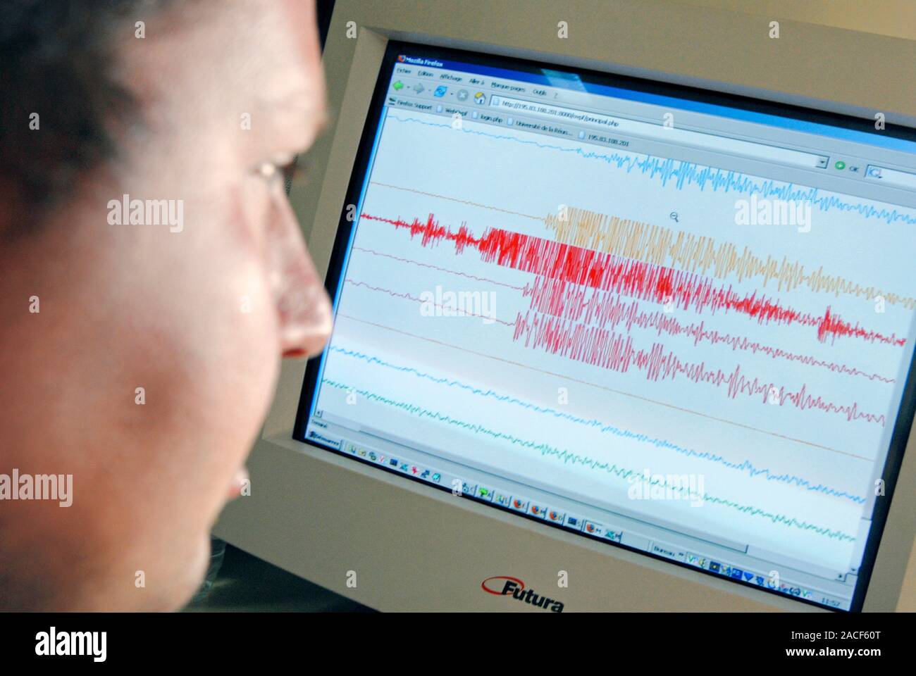 Seismic survey. Researcher looking at a computer readout of seismic ...