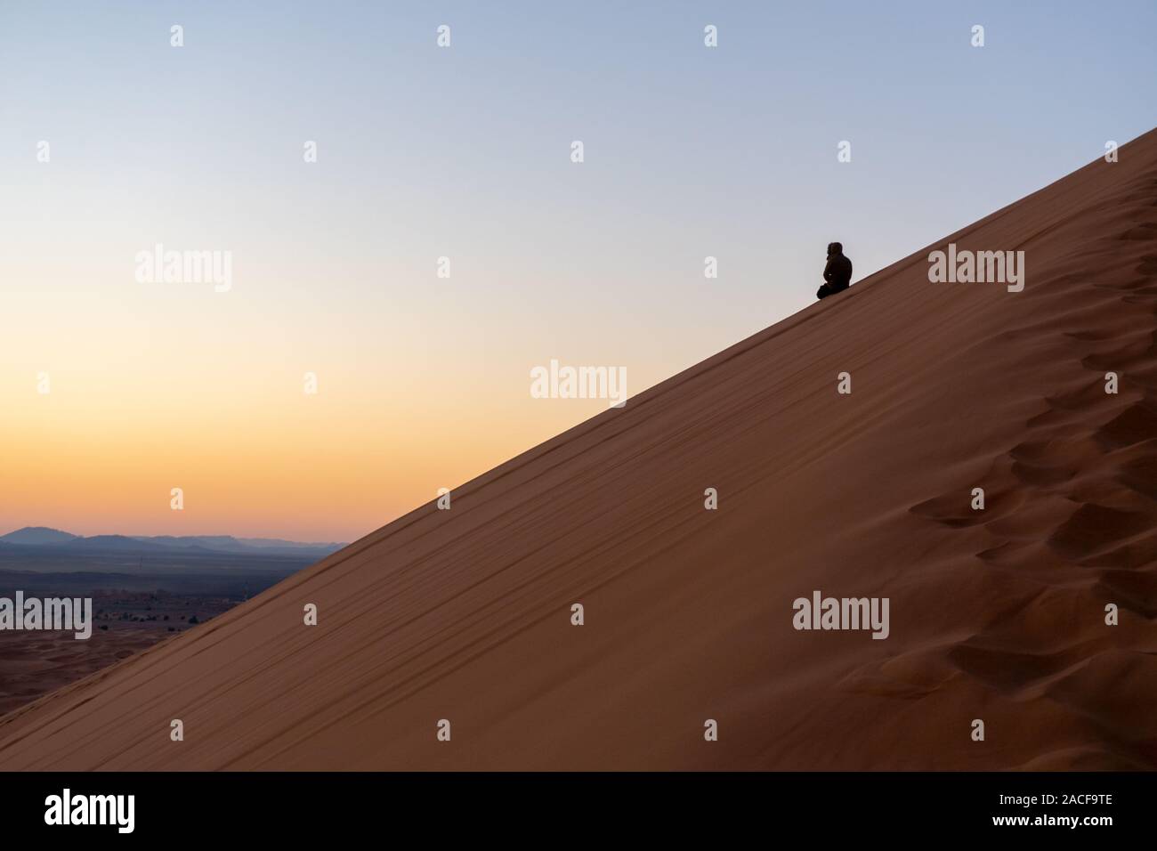 Man on the slope of Sand dune of Erg Chebbi in the Sahara Desert, Morocco Stock Photo