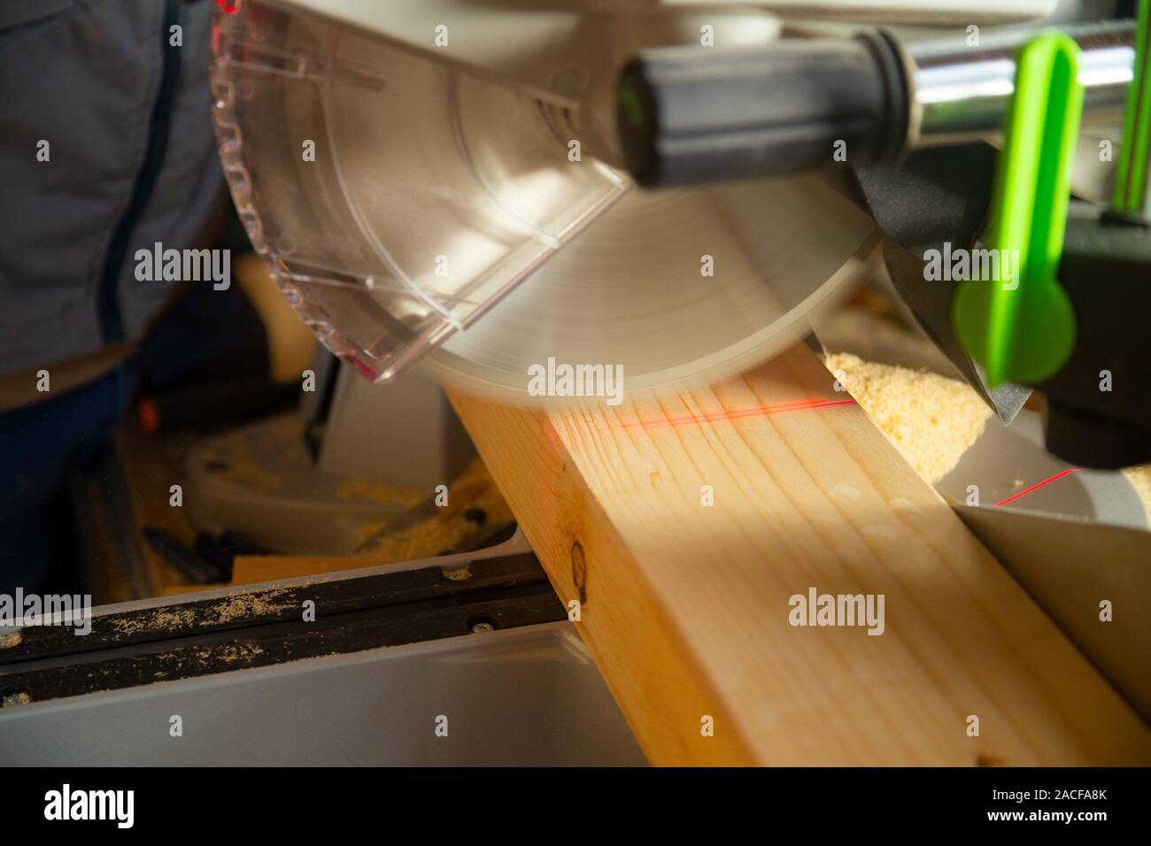 Closeup of carpenter cutting a piece of wood with a modern table saw Stock Photo