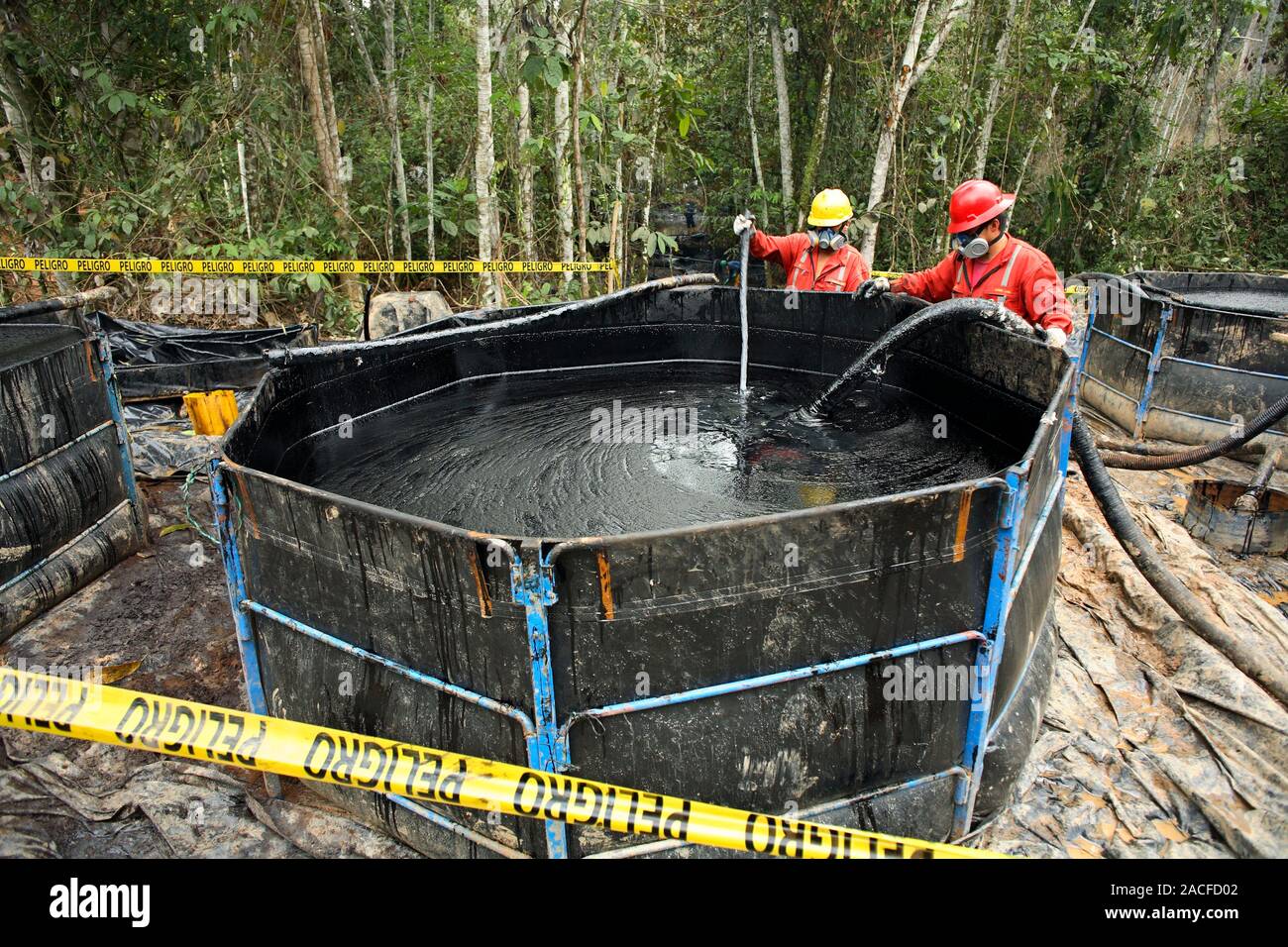 Oil spill damage control in a rainforest. Workers monitoring and