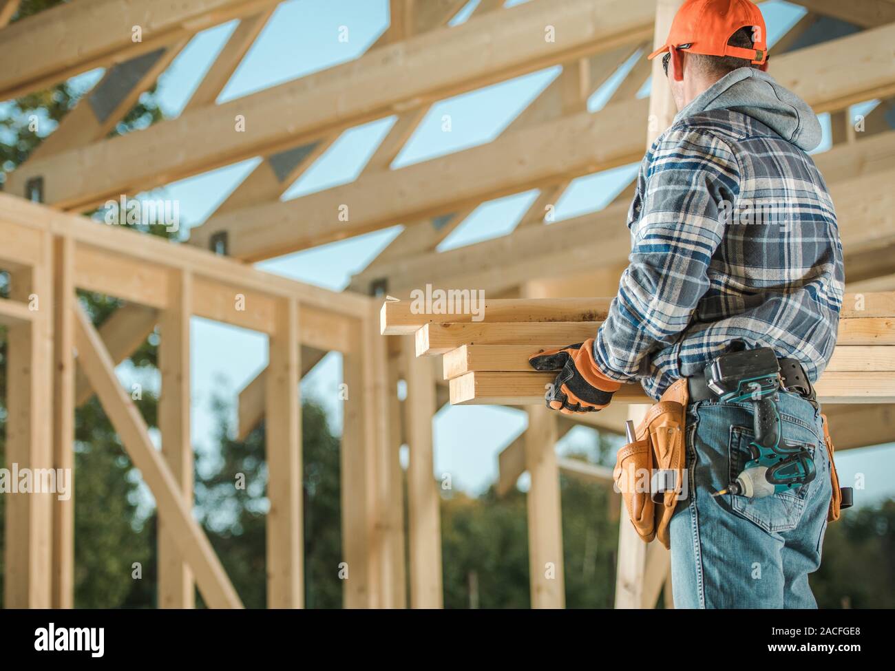 Wood House Construction Technologies. Caucasian Carpenter Contractor Worker with Wooden Elements For the Frame. Industrial Theme. Stock Photo