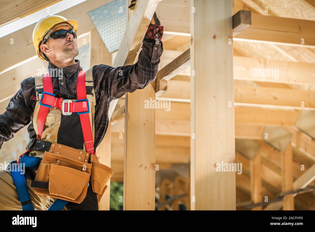 Wood Frame House Building Technologies. Caucasian Construction Contractor in His 30s. Industrial Theme. Stock Photo