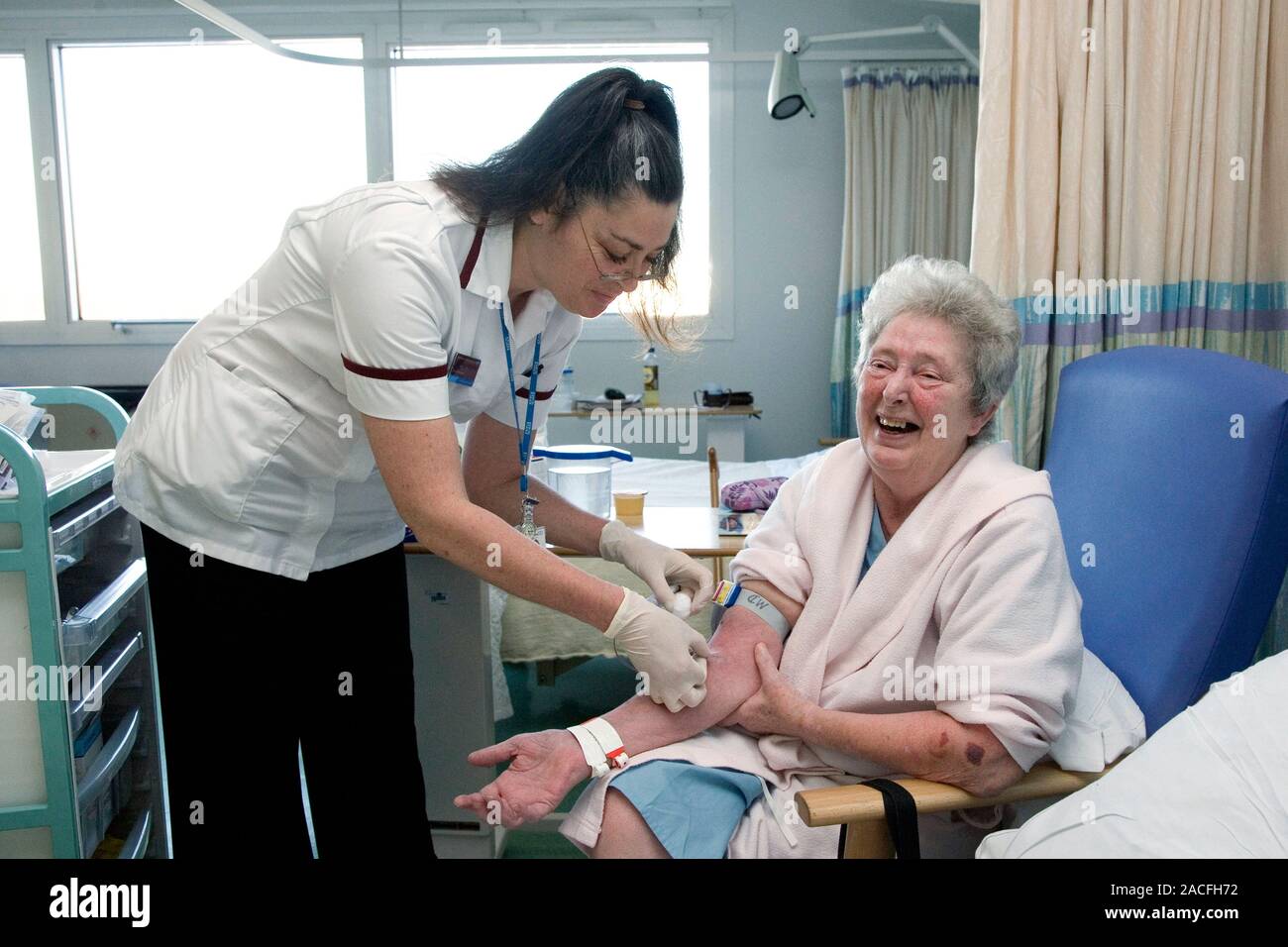 Taking blood. Nurse removing a cannula from the arm of an elderly ...