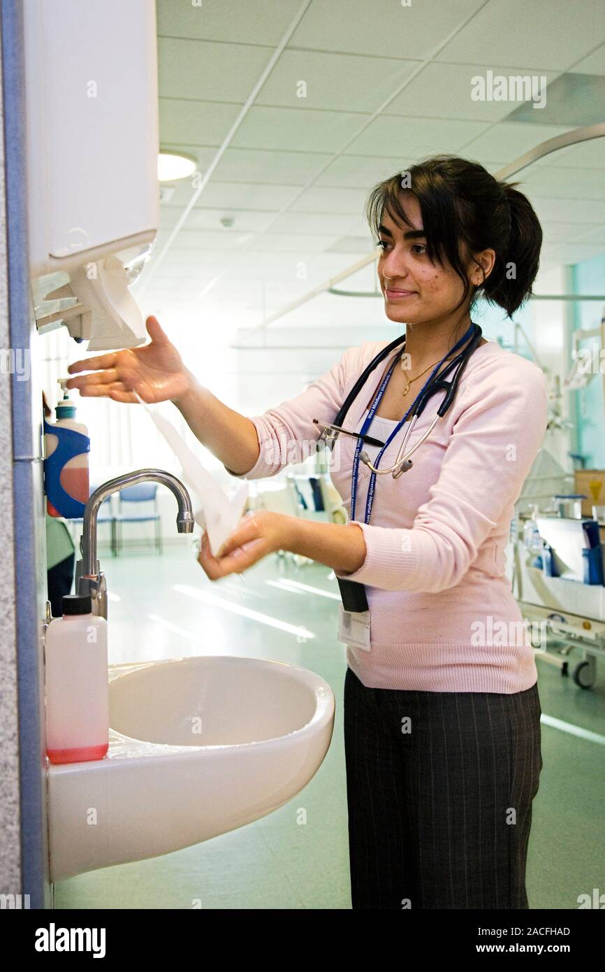 Hospital hygiene. Doctor using a paper towel to dry her hands after washing them at a hand wash