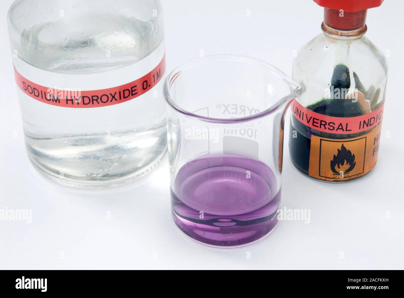 Detecting an alkali. Beaker of sodium hydroxide solution (NaOH, left) and bottle of universal