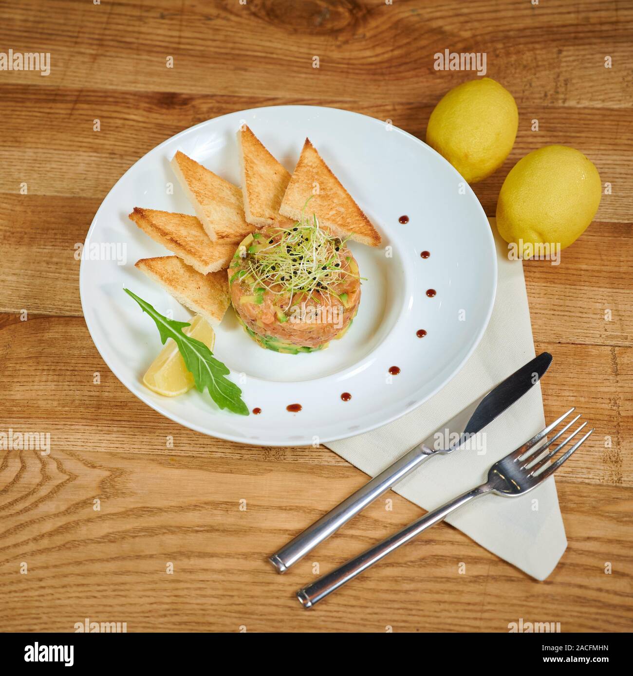 Delicious salmon tartare with avocado. Arrangement with a glass of wine and cutlery Stock Photo