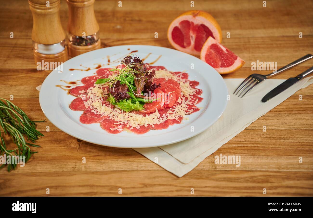 Close up of a beef carpaccio with grapefruit and lettuce in a restaurant Stock Photo
