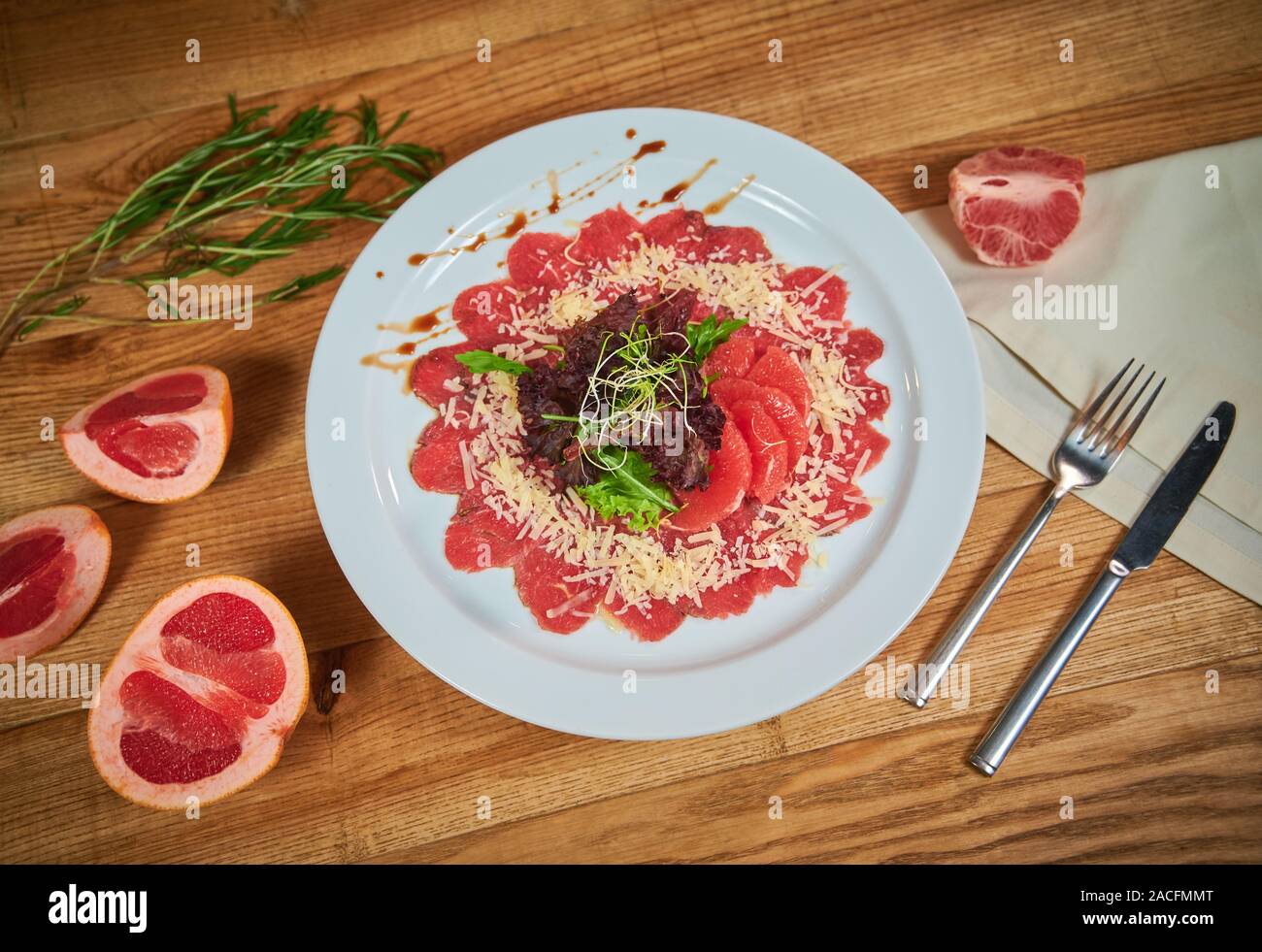 Beef carpaccio with grapefruit and lettuce. Arrangement with cutlery Stock Photo