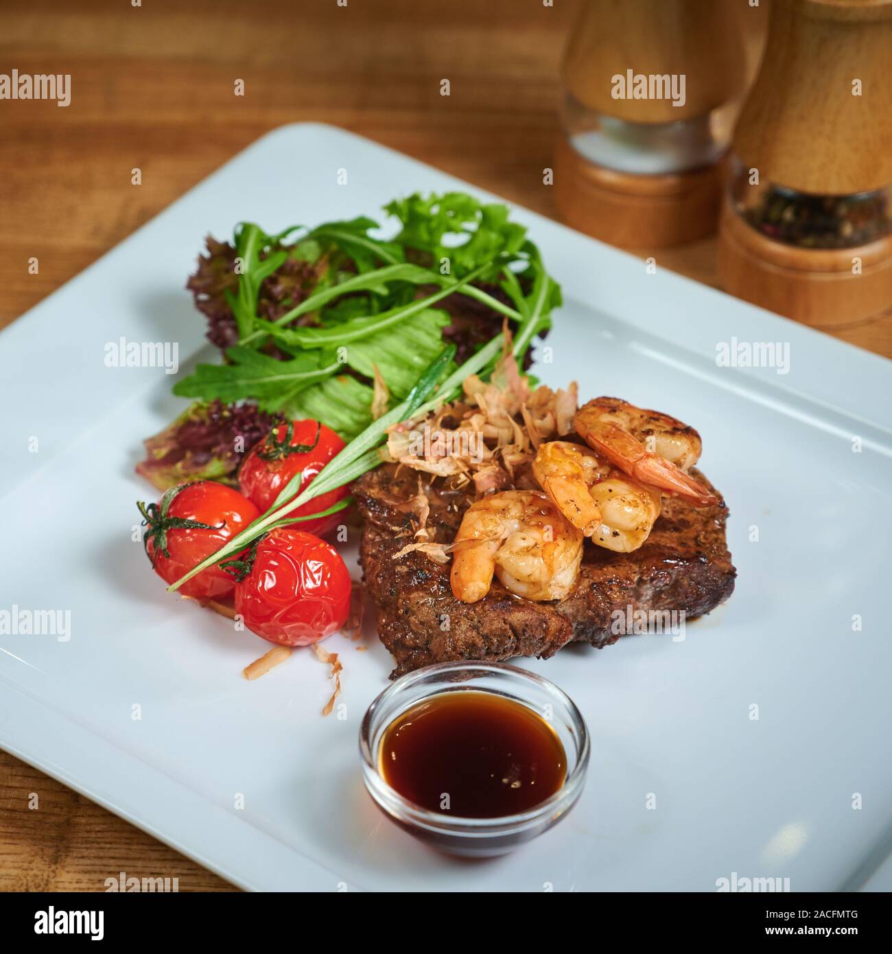 Dish of meat on a plate adding with shrimp, tomatoes and salad. Grilling steak Stock Photo