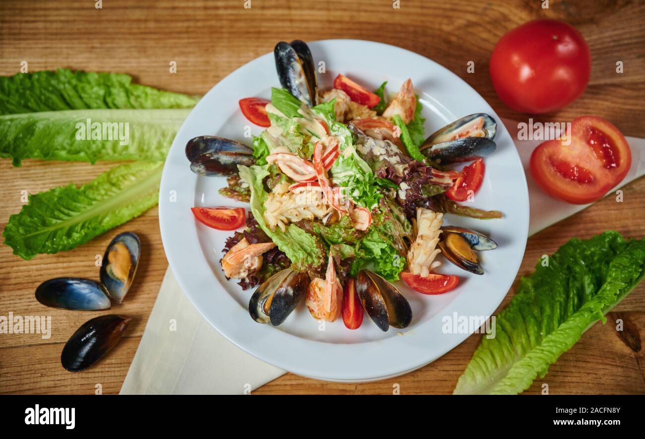 Delicious healthy salad with shrimp, mussels, tomatoes and lettuce leaf, close-up Stock Photo