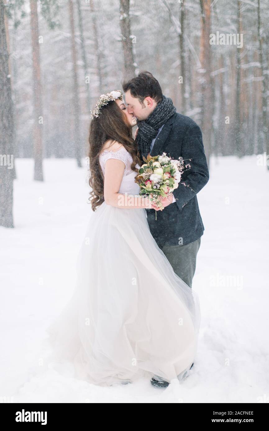 Winter wedding couple, bride and groom hugging and kissing in the snowy ...