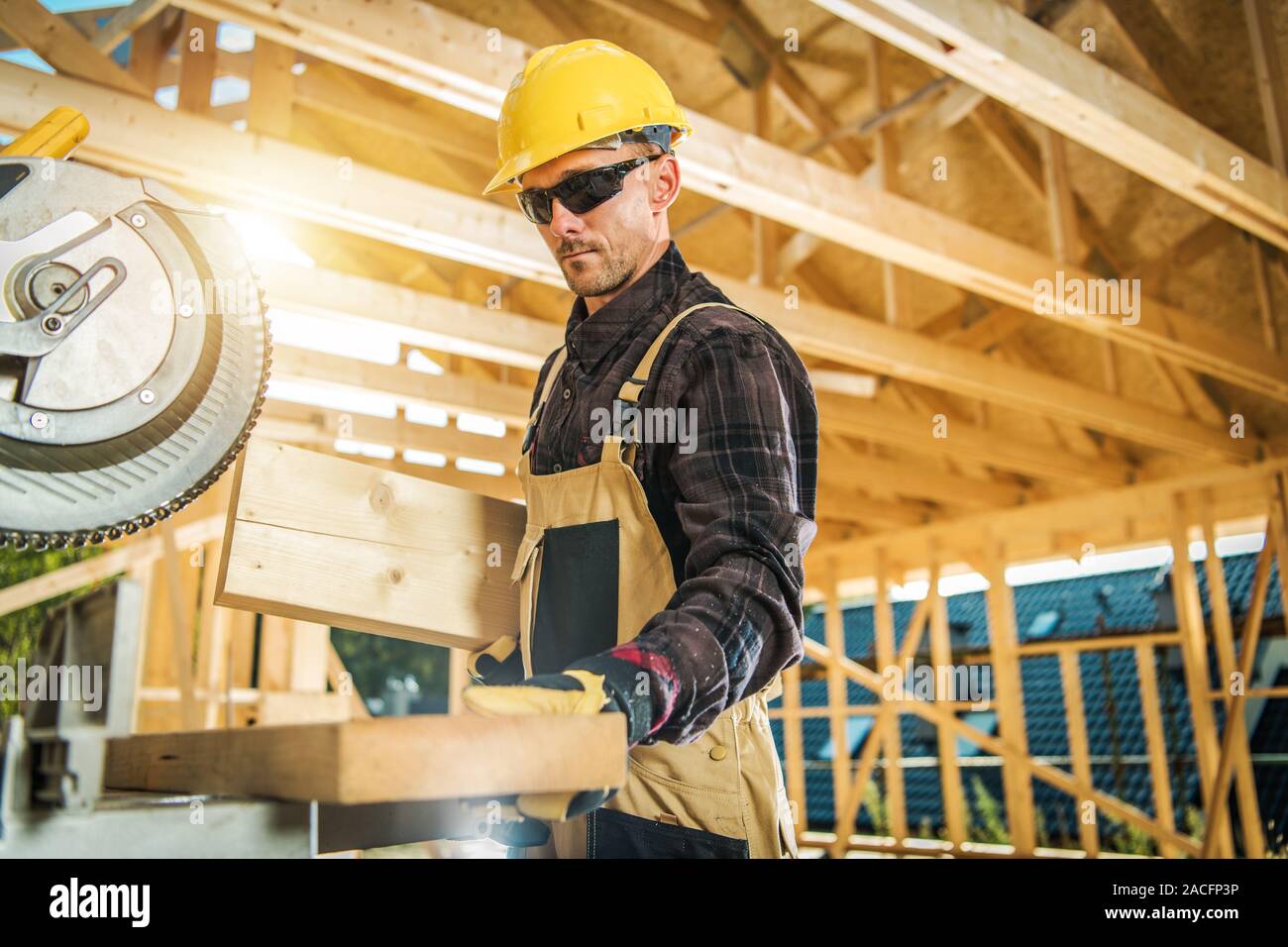 Caucasian Carpenter Worker and the Wooden House Skeleton Frame. Construction Industry Theme. Stock Photo