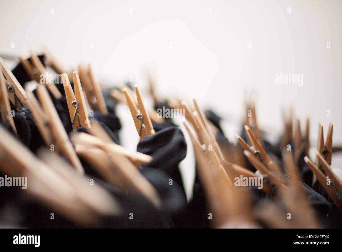 Wooden clothespins on the clothesline with black clothes hanging with unfocused background Stock Photo