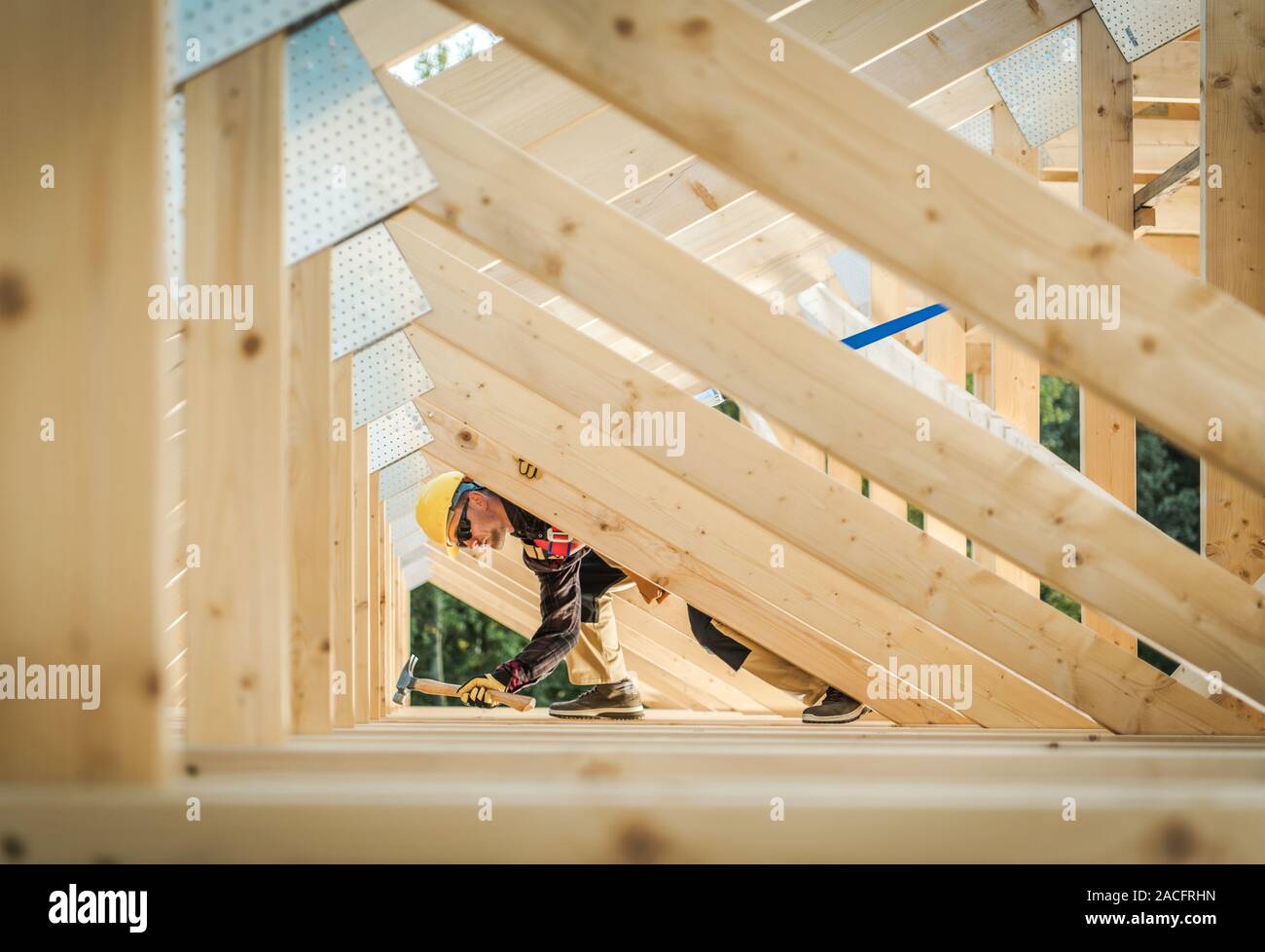 Wooden Home Frame Construction. Caucasian Contractor in His 30s Wearing Hard Hat. Residential Construction. Stock Photo