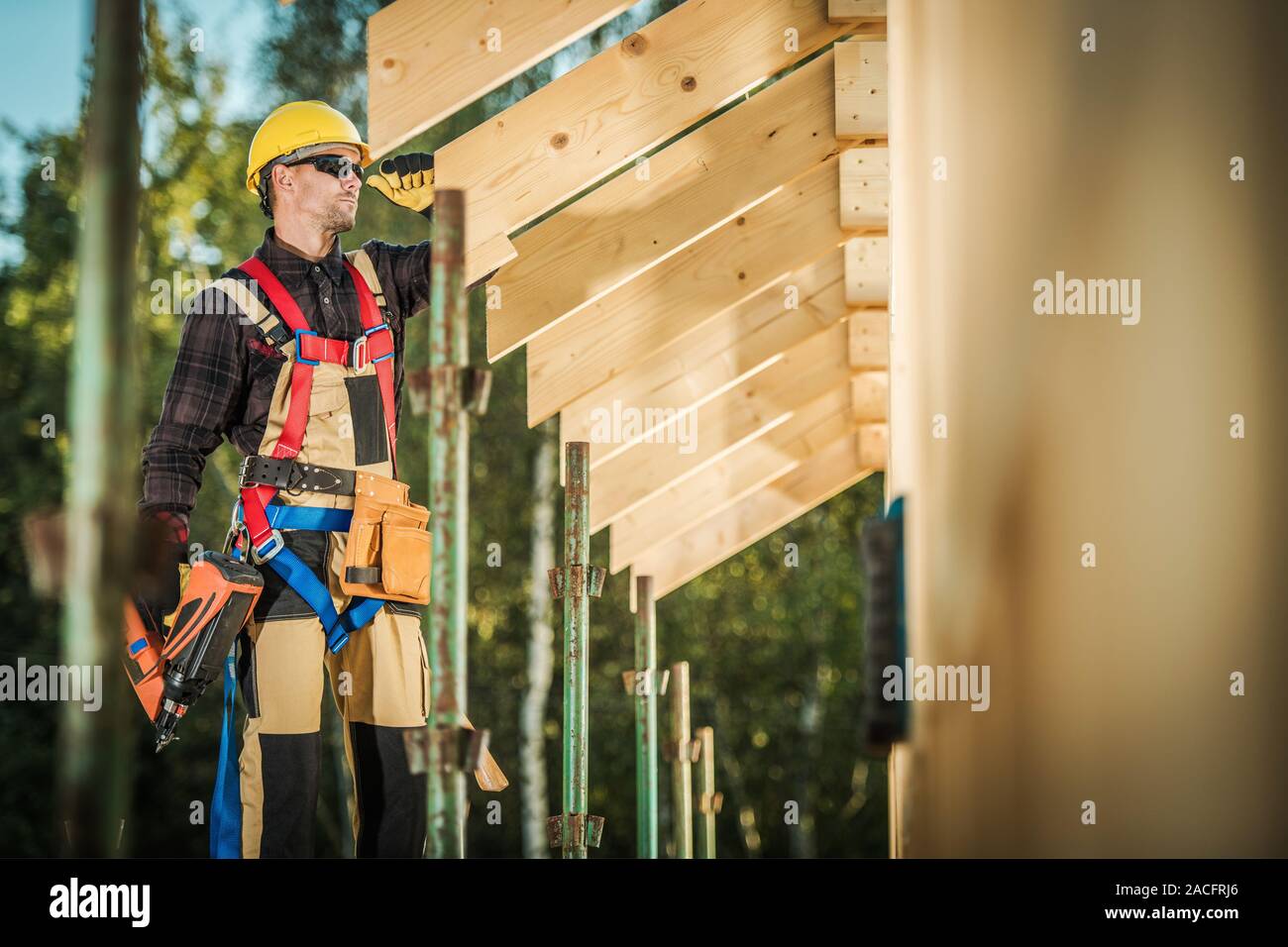Construction Worker with Nail Gun in a Hand. Contractor and His Wood Framing Job. House Building. Stock Photo