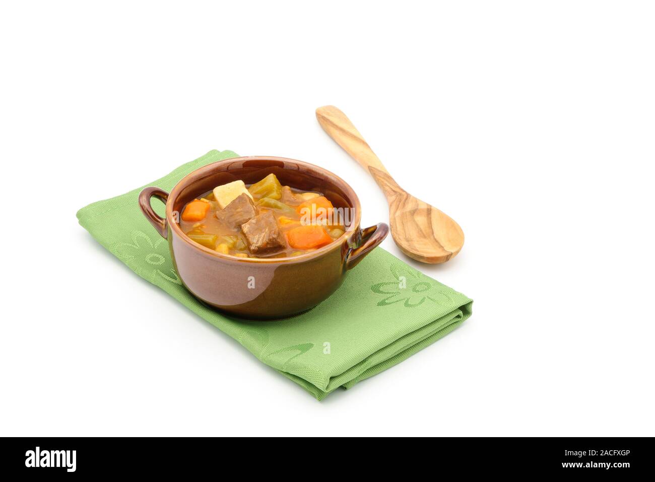 Bowl of hearty beef stew on a green napkin on a white background photographed from a high angle. Stock Photo