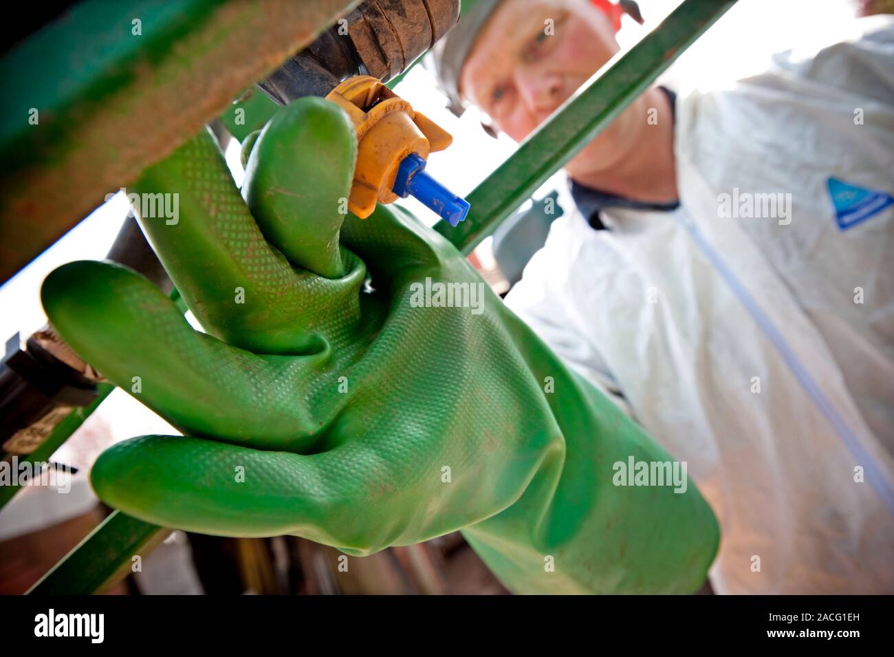 Crop spraying. Operator preparing to add pesticide to a crop sprayer's ...