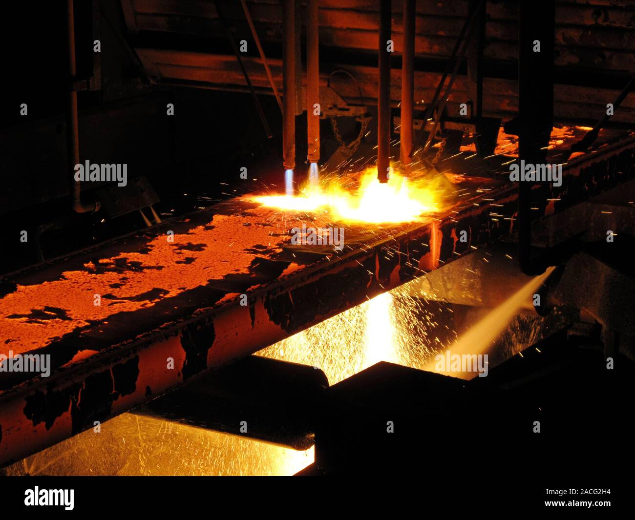 Molten steel bars being cut using gas torches inside a metal working