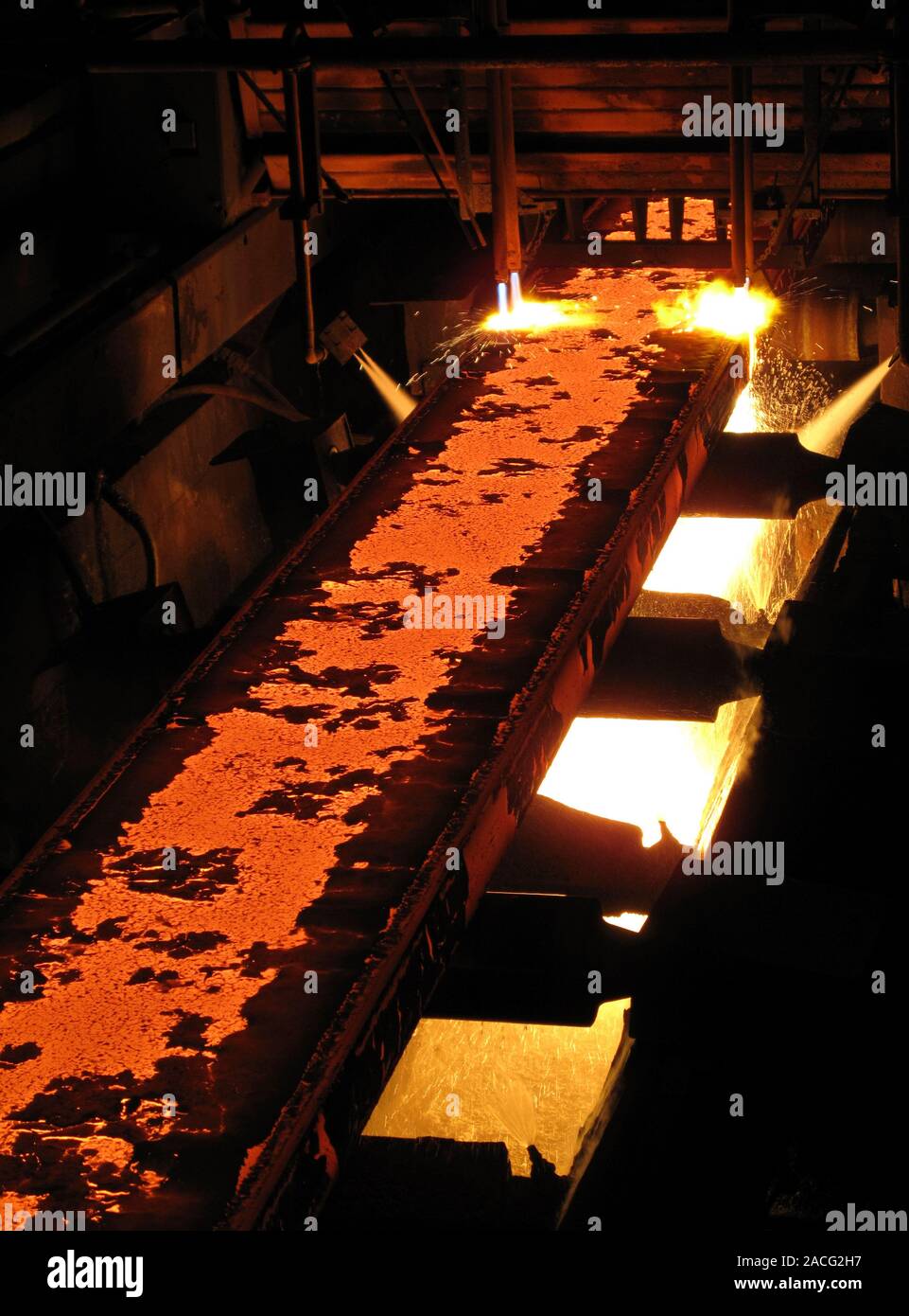 Molten steel bars being cut using gas torches inside a metal working