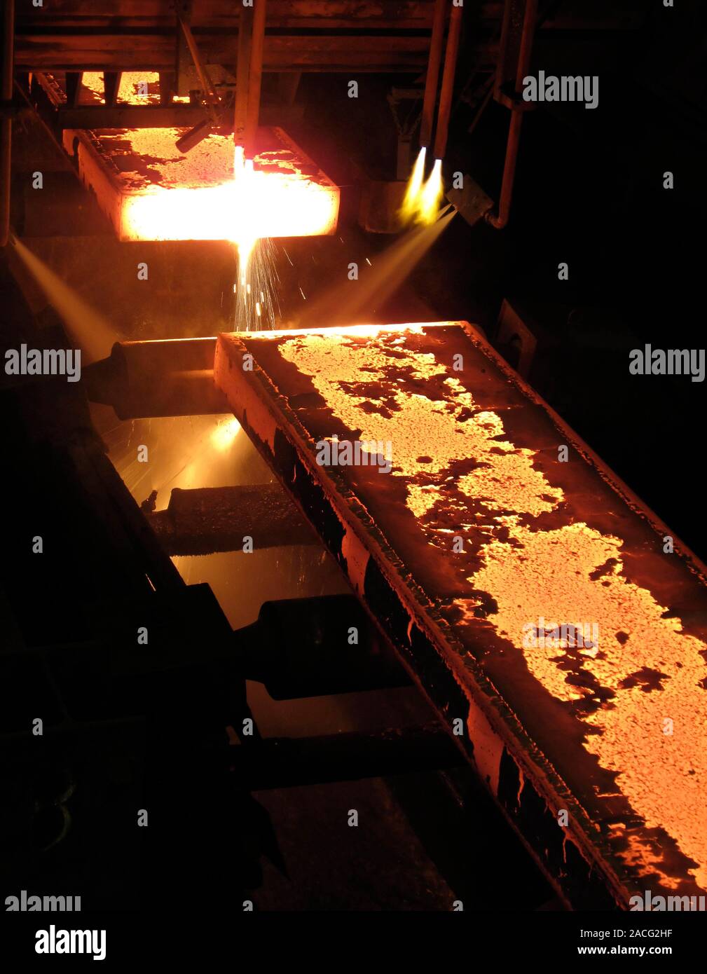 Molten steel bars being cut using gas torches inside a metal working
