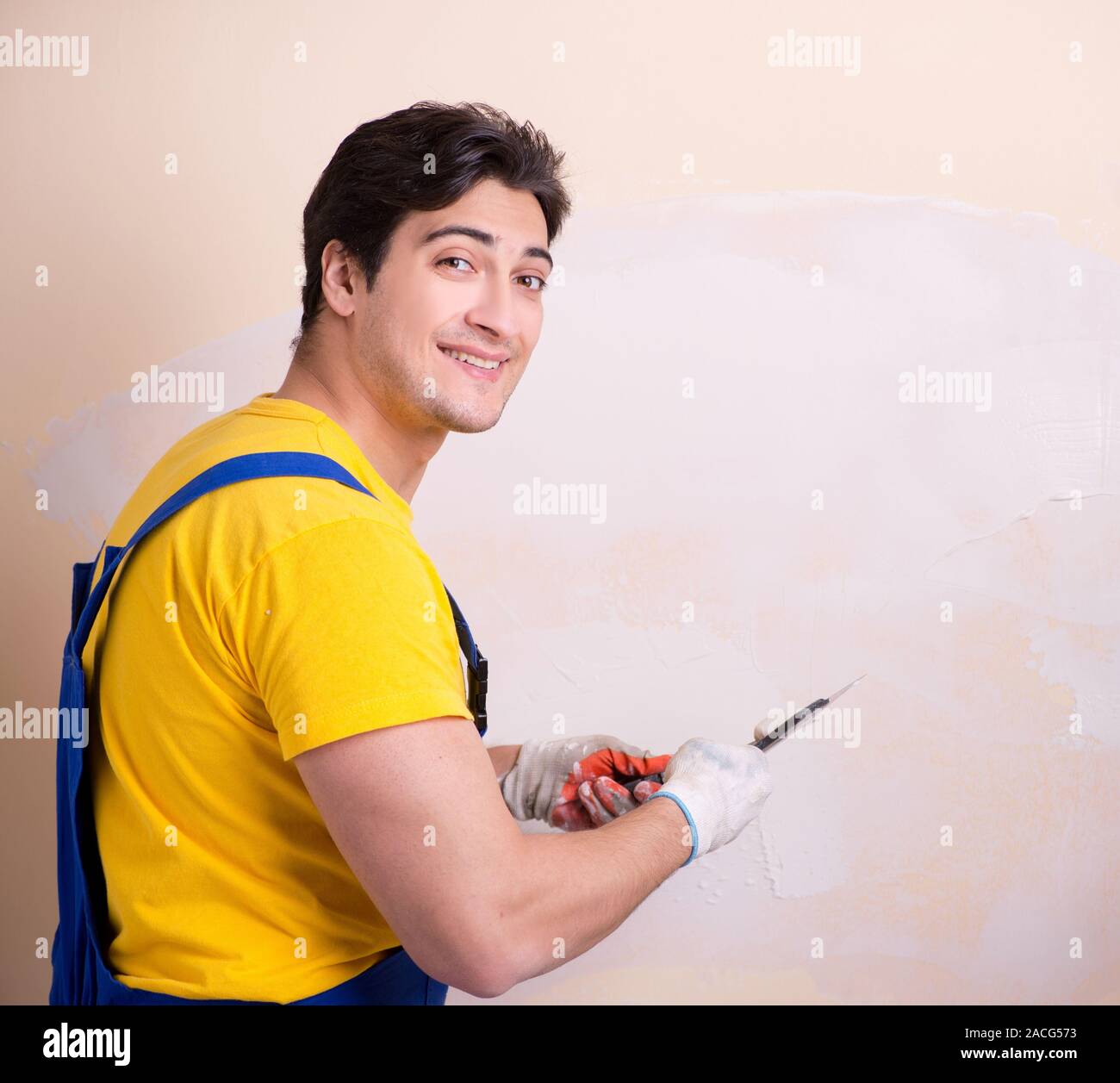 The young contractor employee applying plaster on wall Stock Photo
