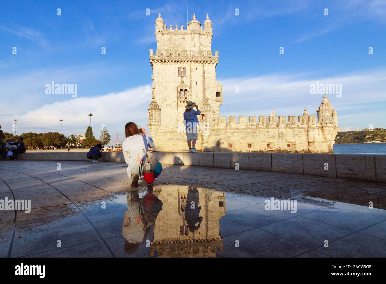 Lisbon, Portugal : Tourists take photos of the Belém Tower reflected on a puddle. The Unesco listed building was designed in 1515 by Francisco de Arru Stock Photo