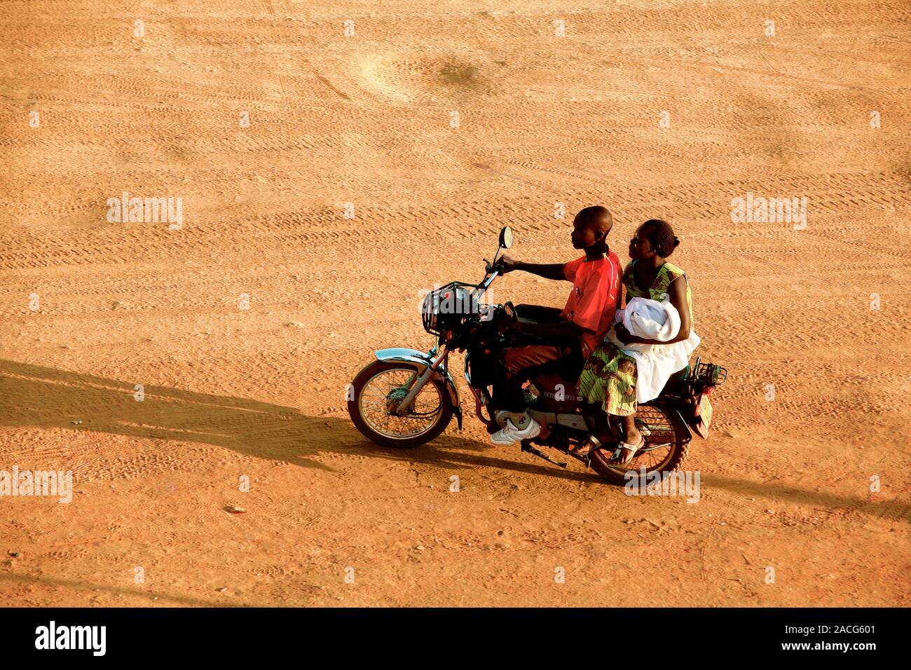 Riding a motorbike. Young man and a woman using a motorbike on an unpaved road. Photographed in Uganda. Stock Photo