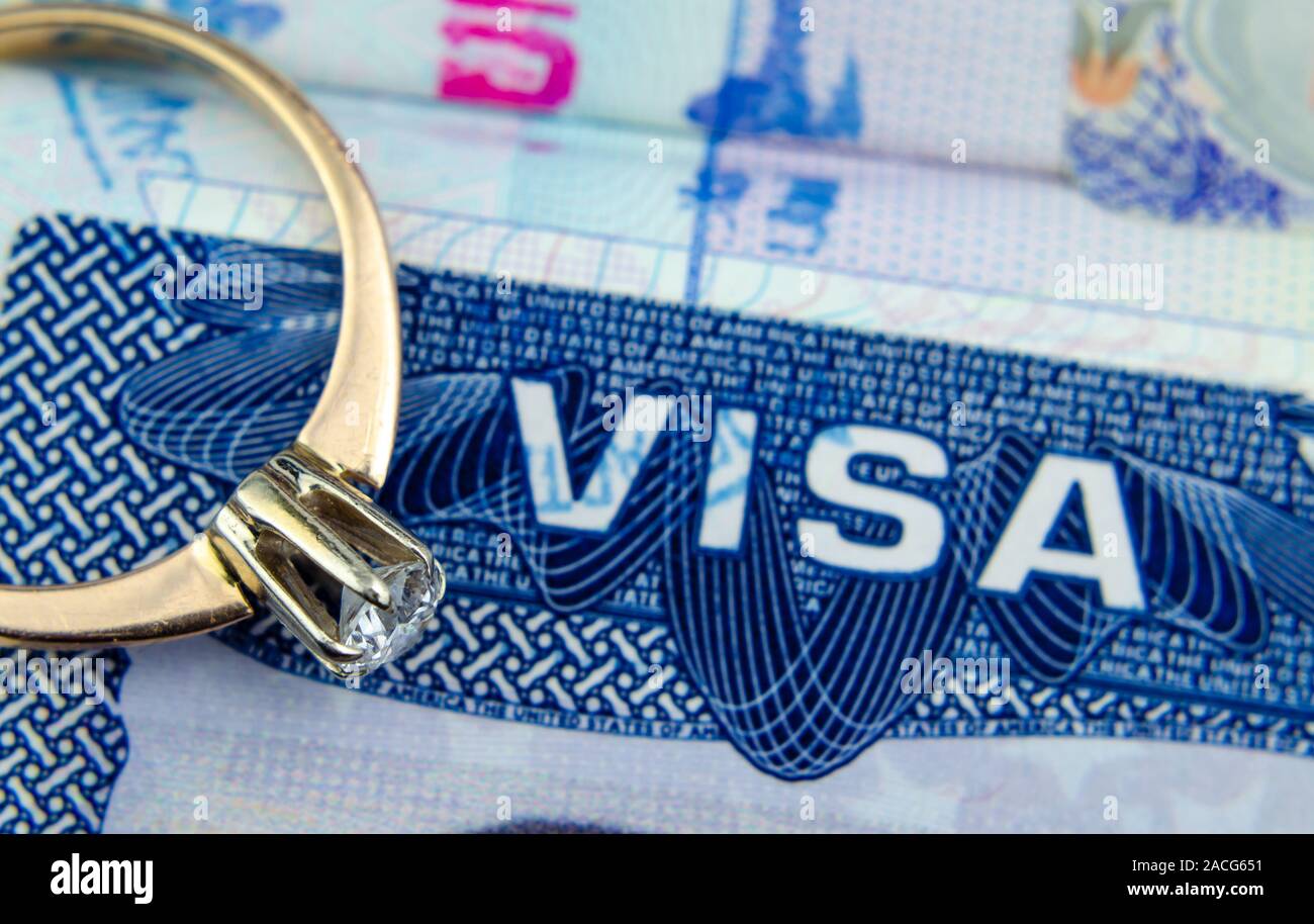 Macro photo of US entry visa sticker in a passport and an engagement diamond ring. Conceptual photo for immigration, spouse / partner / fiance visa. Stock Photo