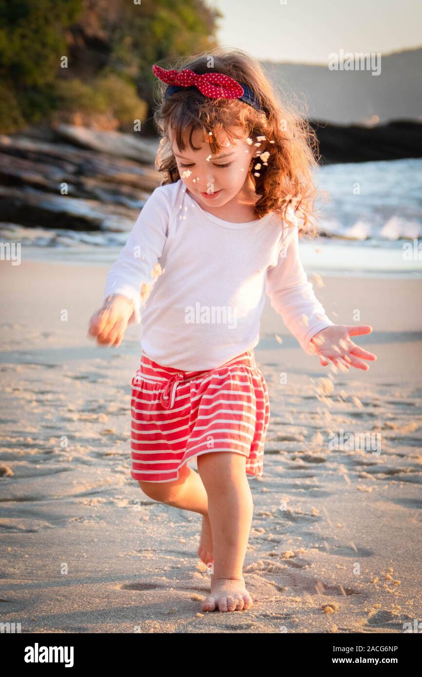 Girl on the beach playing with sand, Brazil Stock Photo