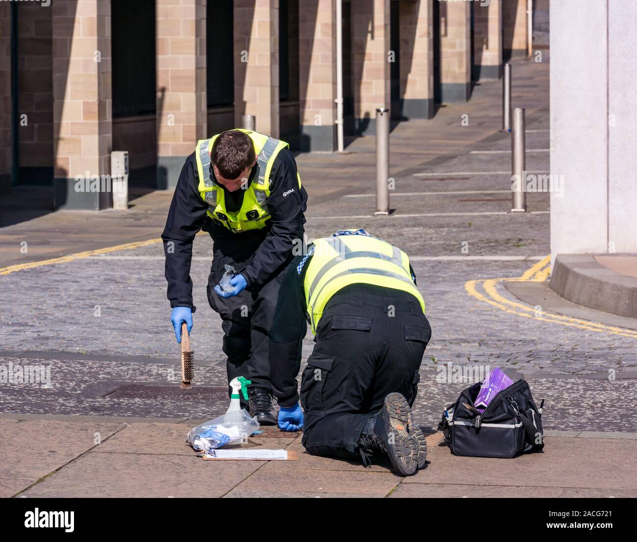 Policemen security checking drains, Holyrood Road near Scottish Parliament, Edinburgh, Scotland, UK Stock Photo