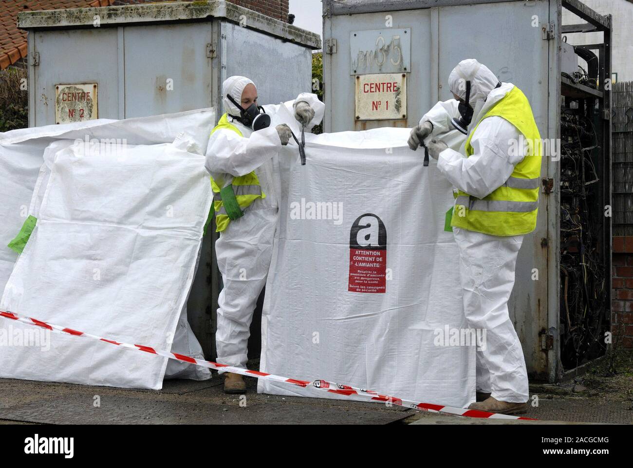 Asbestos removal. Workers in protective clothing dismantling huts 