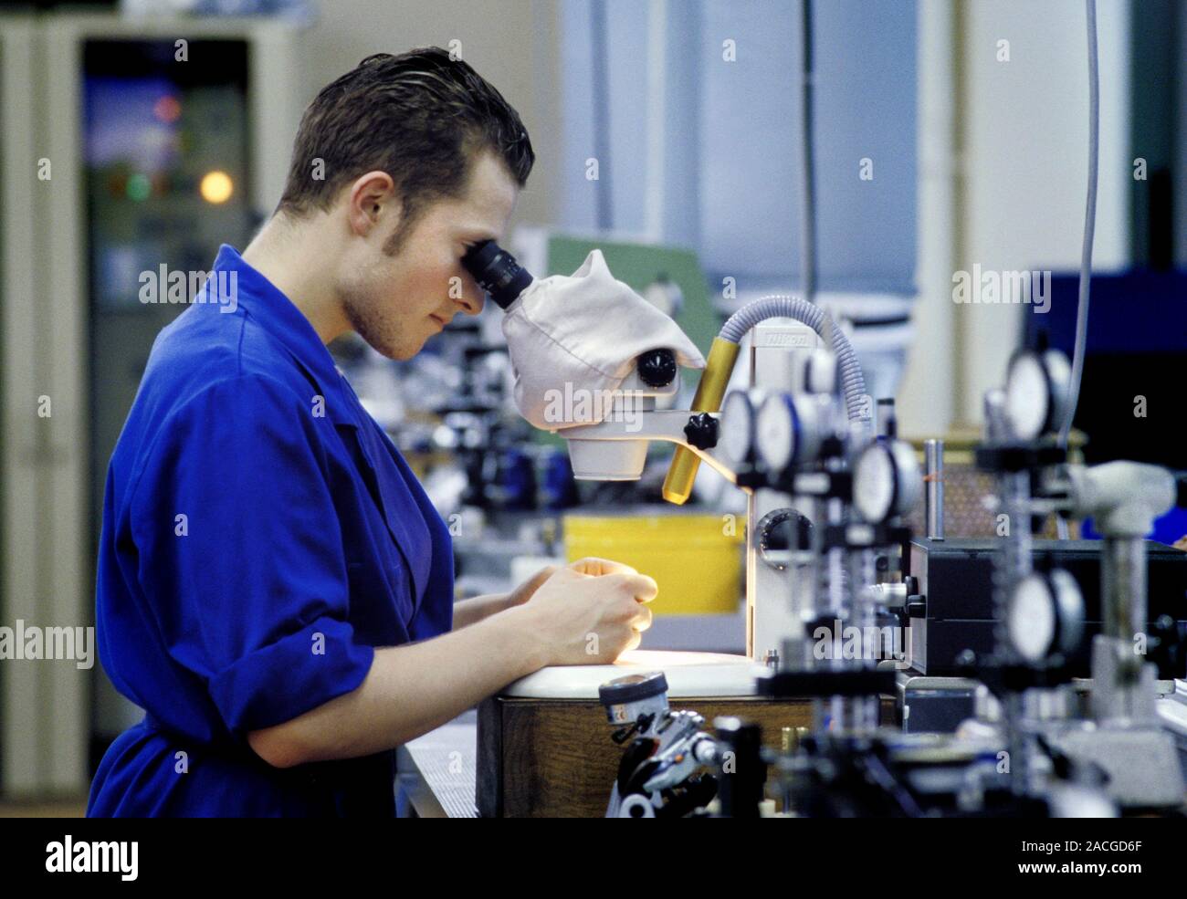 Factory quality control. Technician using a microscope to check the ...