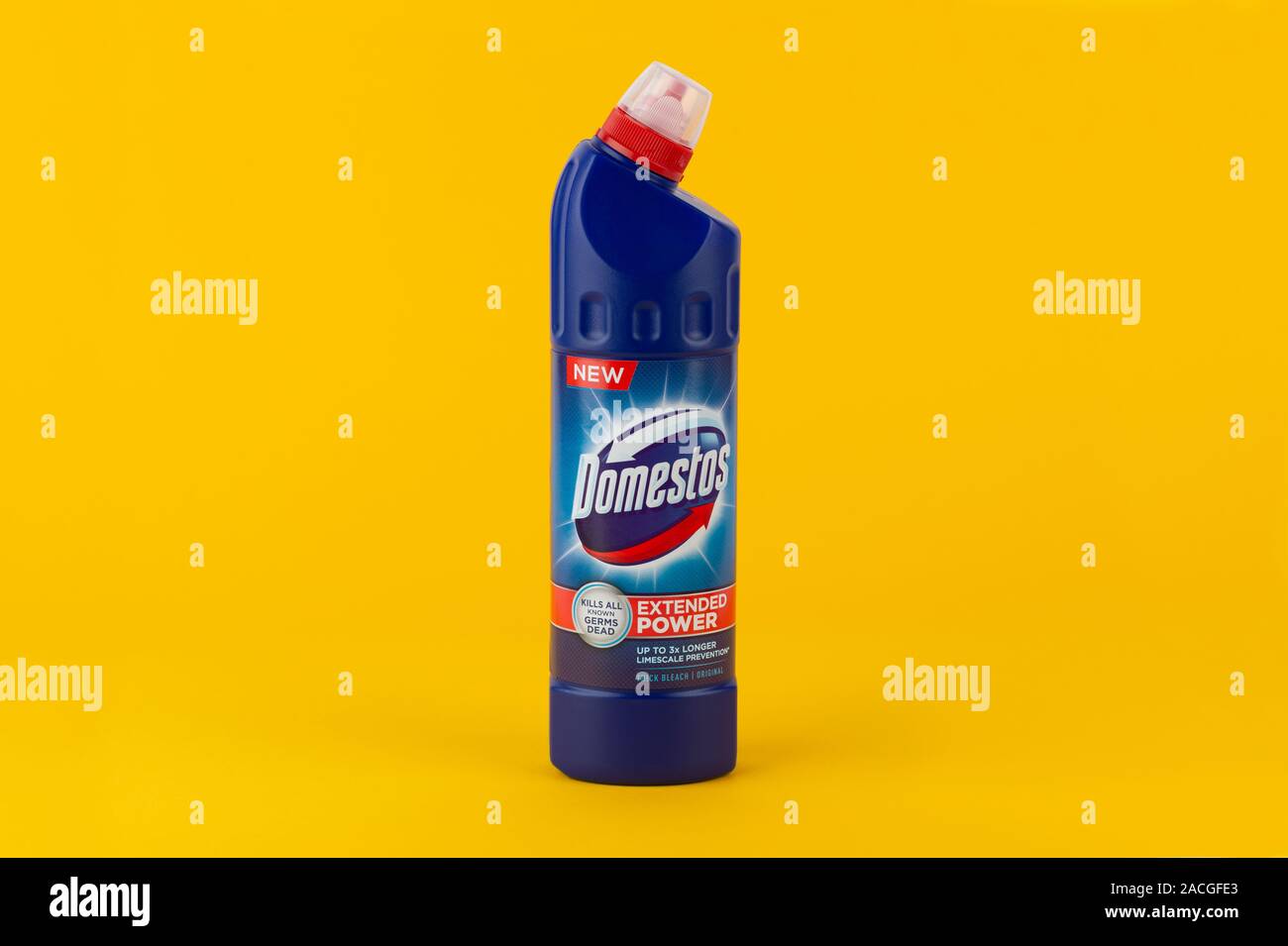 A Domestos bleach bottle shot on a yellow background. Stock Photo