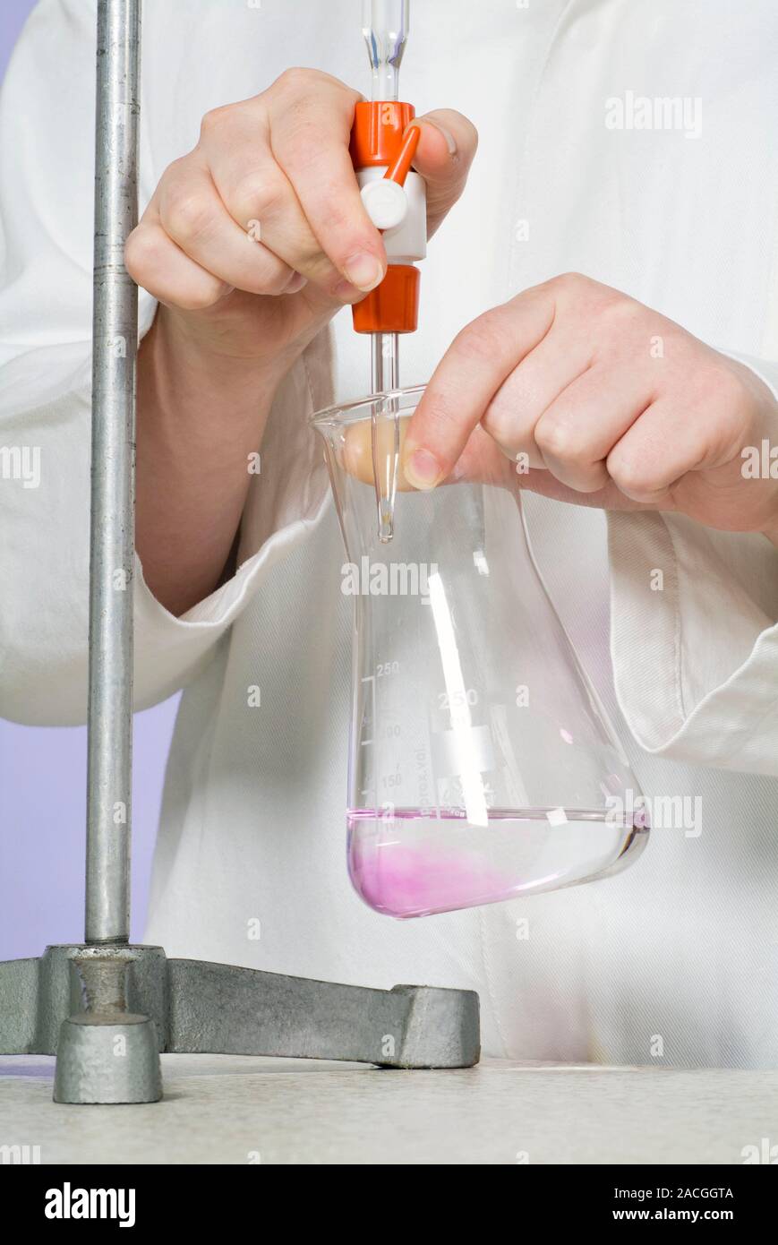 Titration experiment. Student adding an alkaline solution from a
