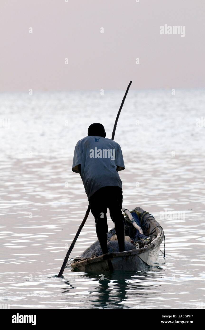 Traditional canoe. Fisherman using a pole to propel a traditional