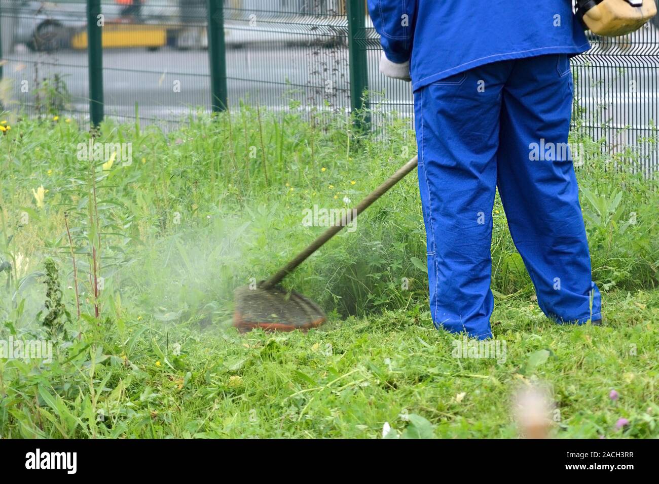Petrol lawn mower. Cut grass around the fence. Fire safety Stock Photo