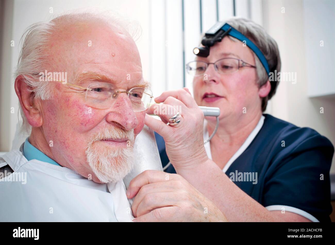 Ear wax removal. Man having his ear syringed at a doctor's surgery
