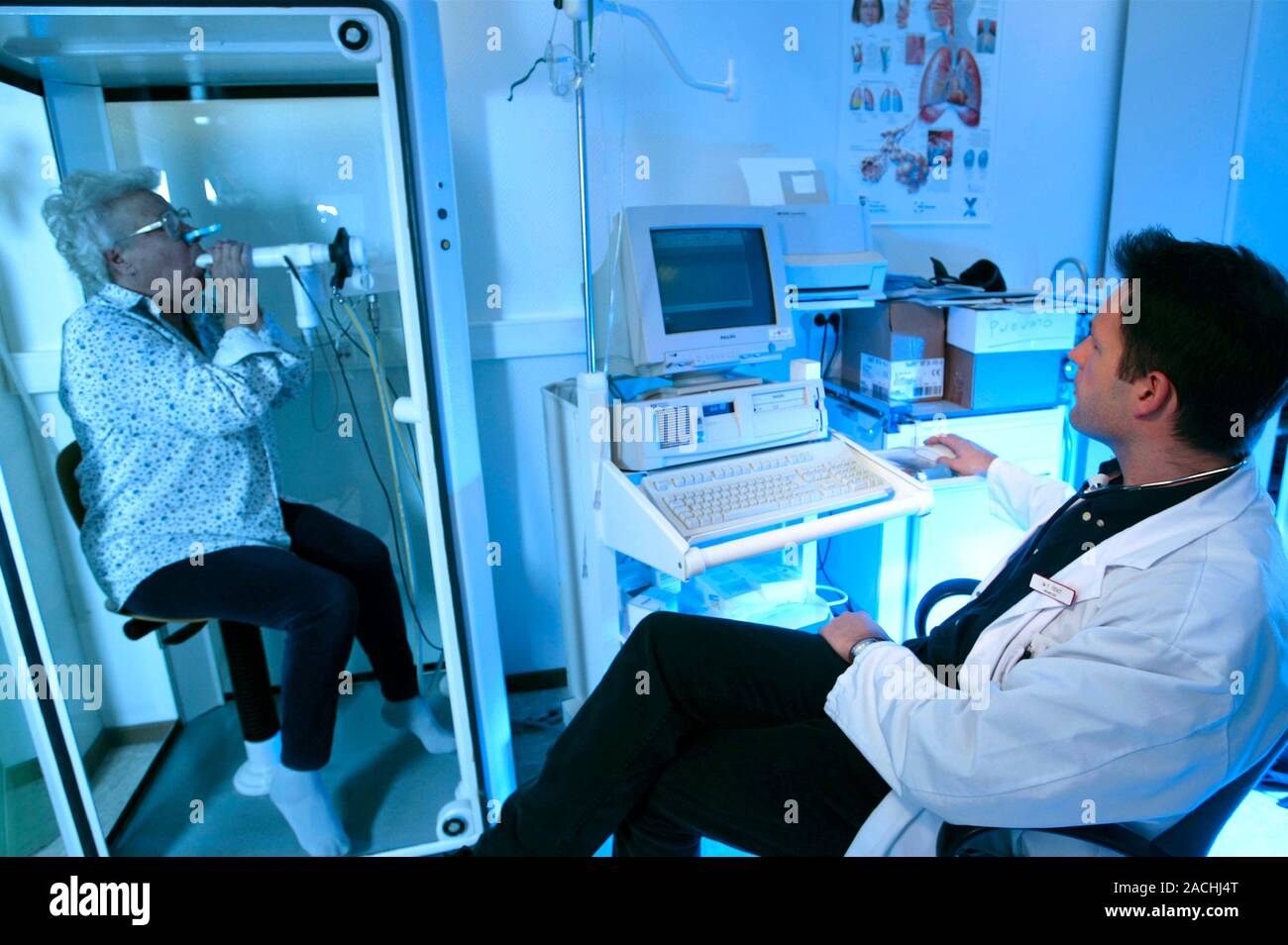 Lung function test. Patient (left) breathing into a peak flow meter