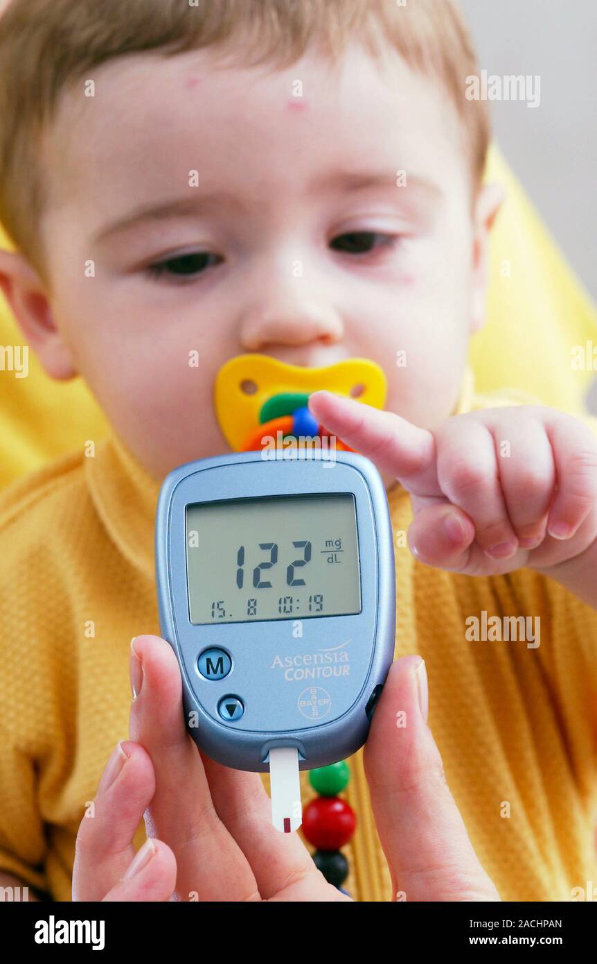 Blood glucose test. Glucometer being used to test a toddler's ...