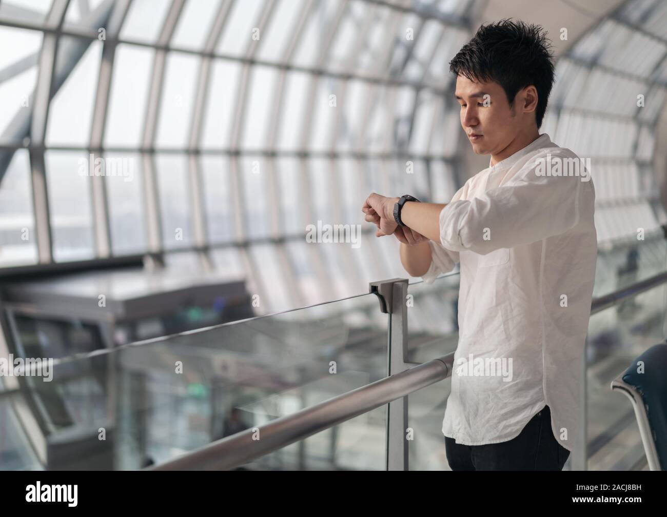 young man waiting for flight and looking smart watch in airport Stock Photo