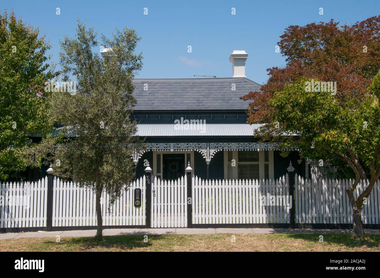 An authentially restored Victorian-era timber house in suburban Melbourne, Australia, featuring slate roof, verandah, iron lacework and picket fence. Stock Photo