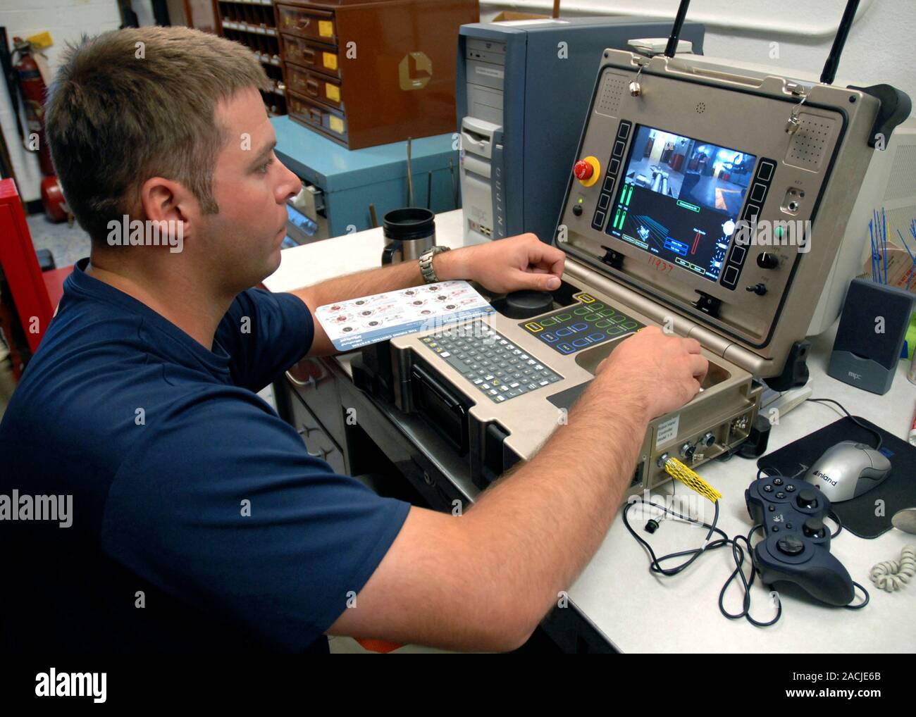 PackBot explosives robot controls. US Navy explosive ordnance disposal (EOD) technician operating a PackBot robot being used to detect and handle expl Stock Photo