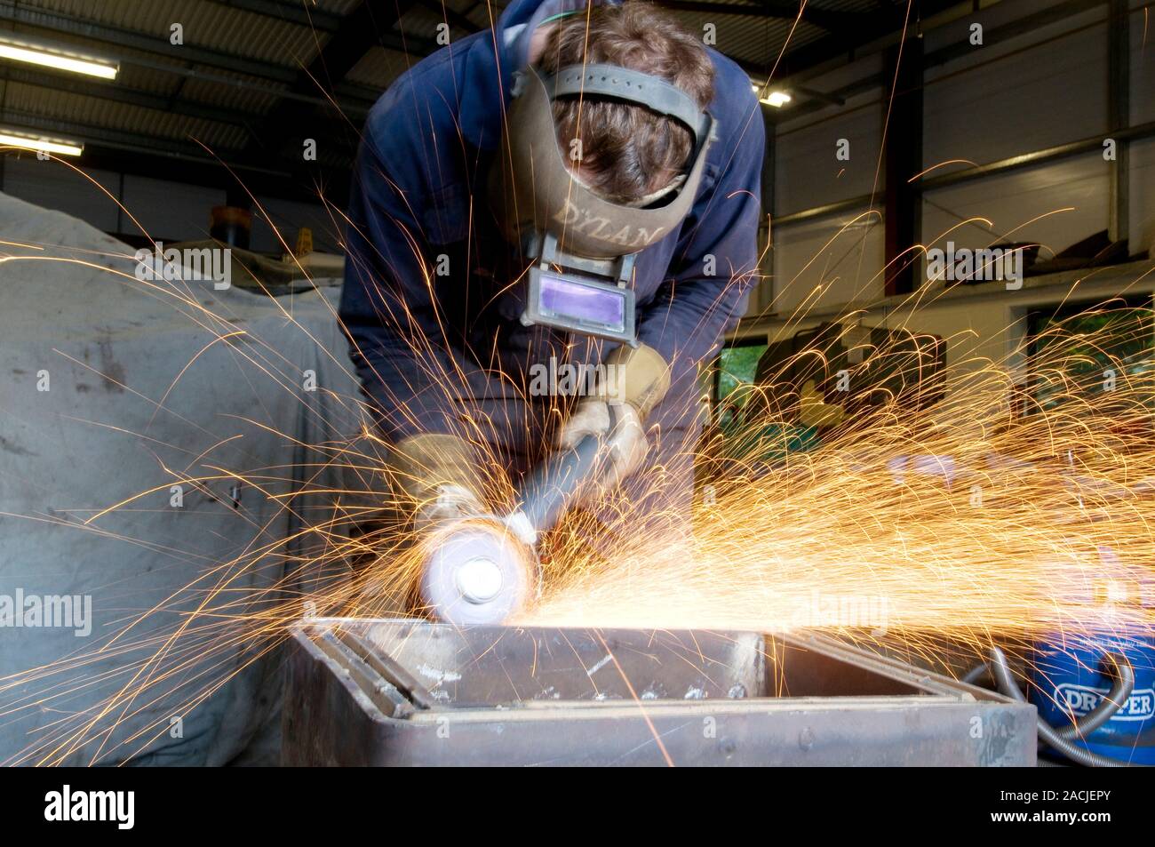 Metal working. Metalworker using an angle grinder in an engineering workshop. Stock Photo